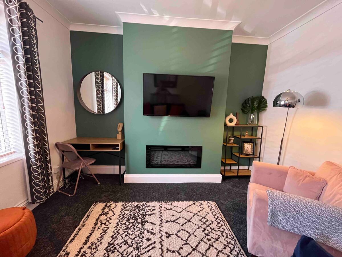 Lounge at the Orla Kiely house, green wall and navy sofa